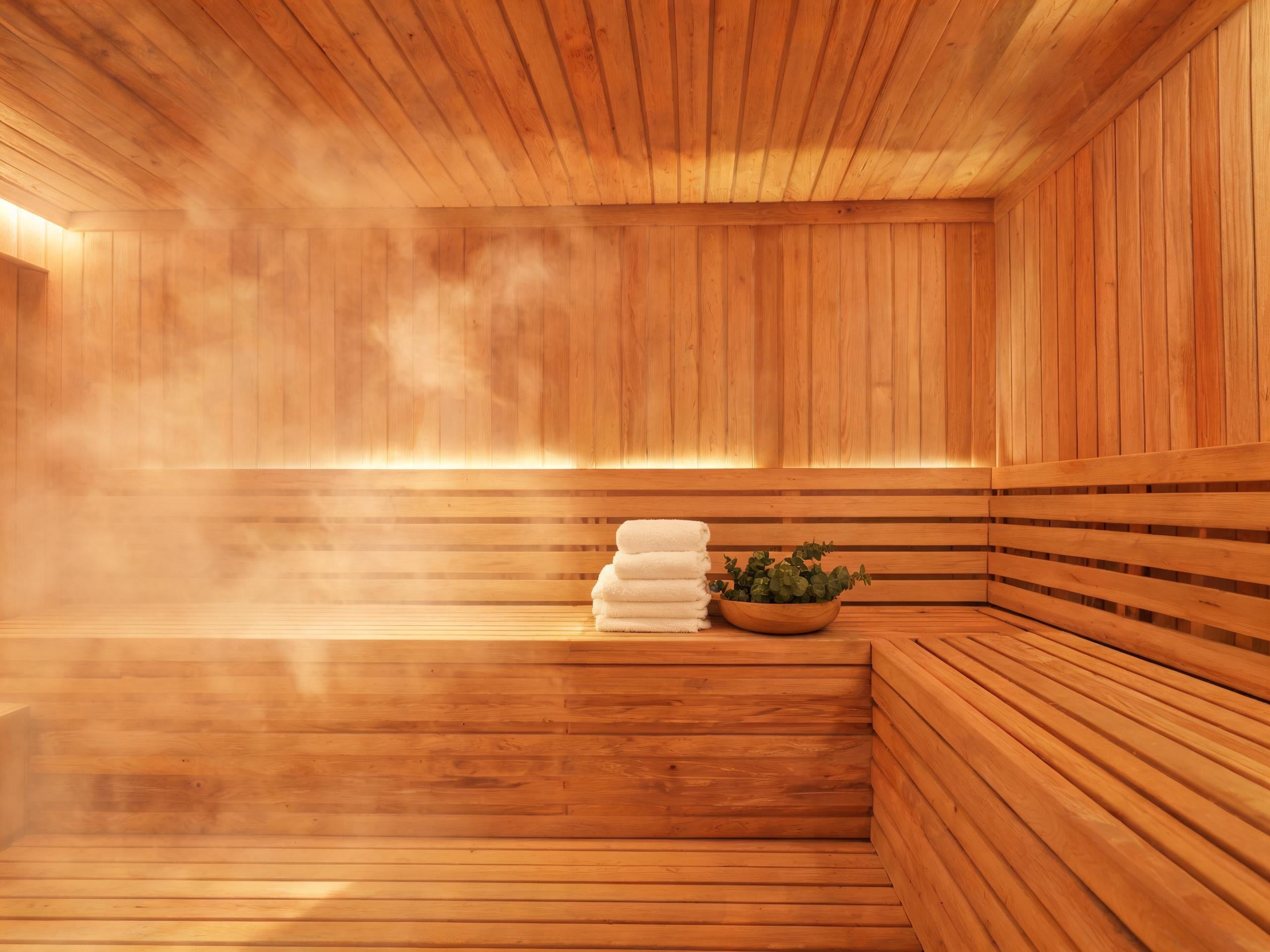 Modernes Sauna-Interieur mit warmem Licht, Handtüchern und Eukalyptuszweigen